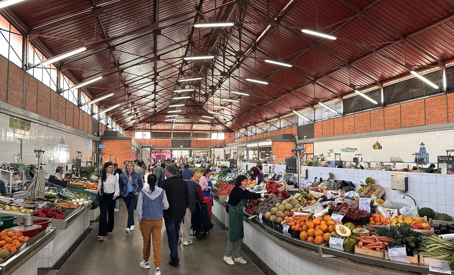 The aisle of an Algarve municipal market, lined with fruit and vegetable stalls